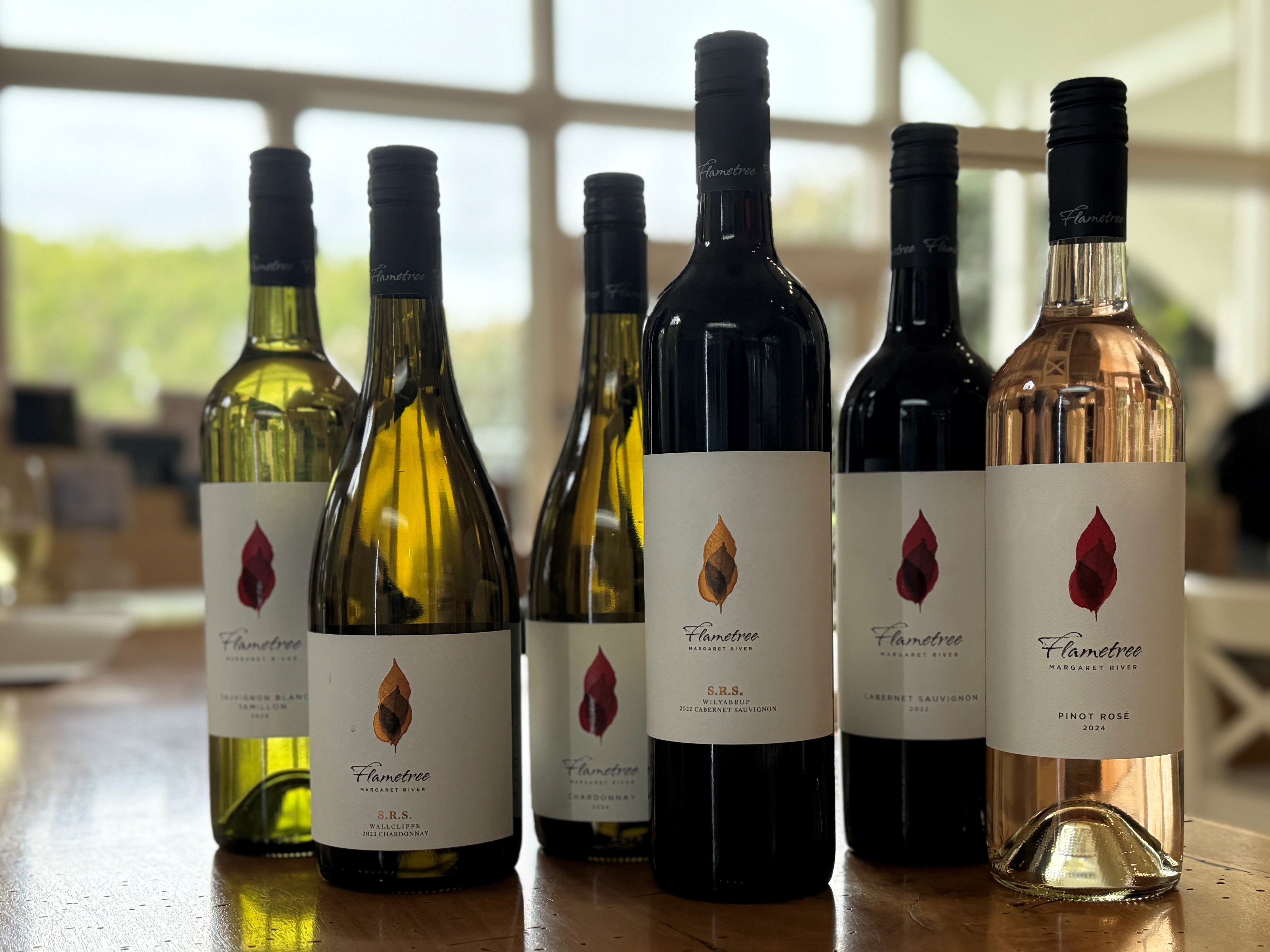 Row of wine bottles on a wooden table with blurred background